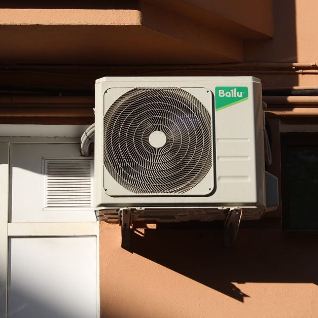 A Ballu air conditioner condenser unit mounted on a building exterior, showcasing modern HVAC technology.
