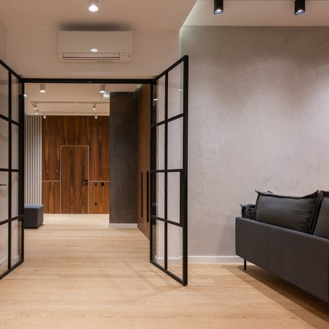 Interior of modern bright house with open doors to hallway near sofa with pillows